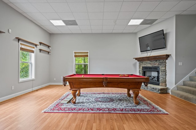 game room with pool table, plenty of natural light, a paneled ceiling, a fireplace, and hardwood / wood-style flooring