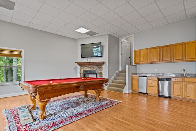 recreation room with sink, light wood-type flooring, a stone fireplace, and billiards