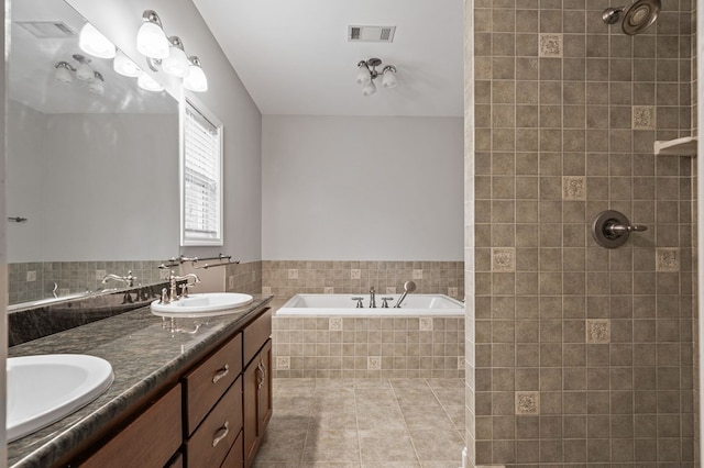 bathroom featuring vanity, a relaxing tiled tub, and tile patterned floors