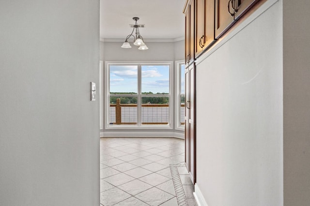 entryway with crown molding, light tile patterned flooring, and an inviting chandelier