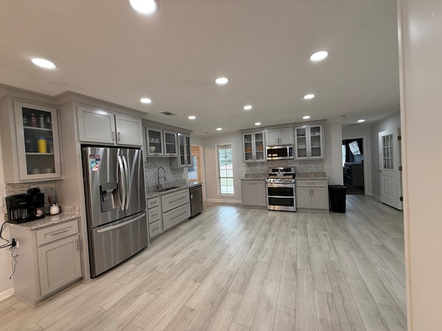 kitchen with light stone counters, gray cabinets, sink, and stainless steel appliances