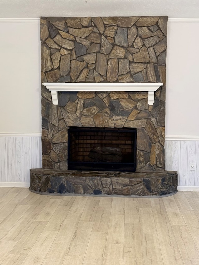 interior details featuring hardwood / wood-style flooring, a stone fireplace, and crown molding