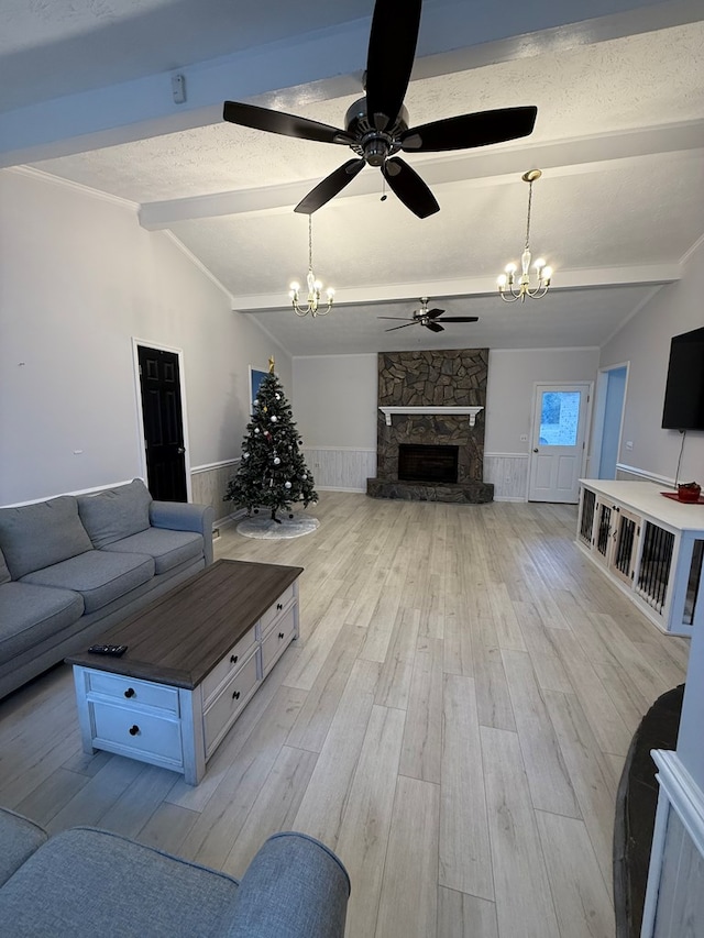 living room with ceiling fan with notable chandelier, lofted ceiling with beams, a textured ceiling, a fireplace, and light hardwood / wood-style floors