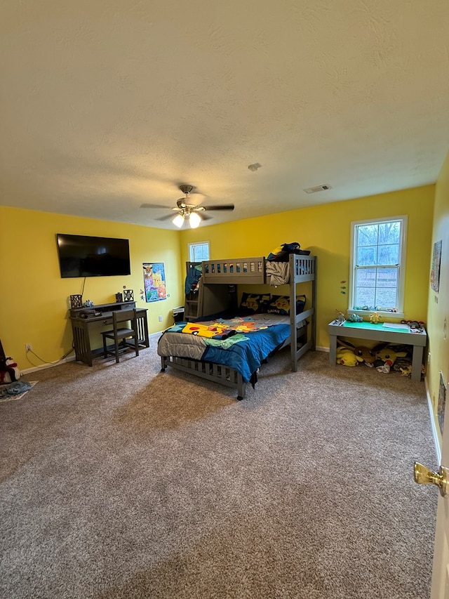 carpeted bedroom with ceiling fan and a textured ceiling