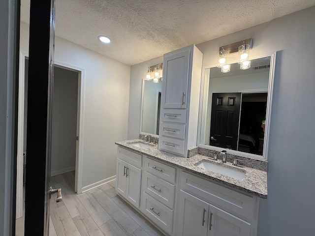 bathroom featuring hardwood / wood-style floors, vanity, a textured ceiling, and a notable chandelier