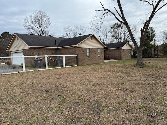 exterior space featuring a lawn, a garage, and central AC