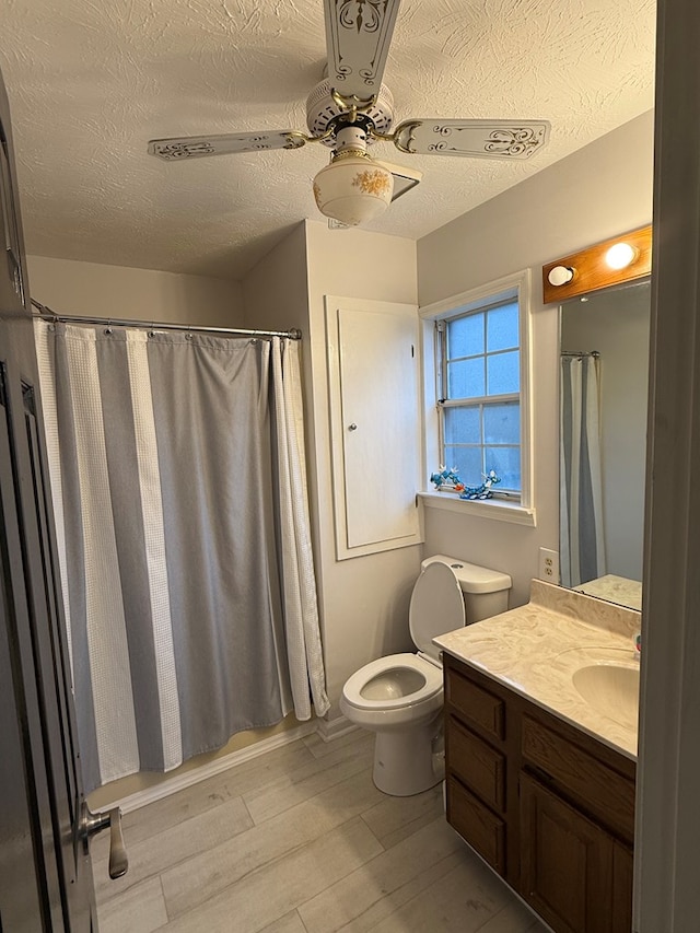 bathroom with vanity, ceiling fan, toilet, a textured ceiling, and wood-type flooring