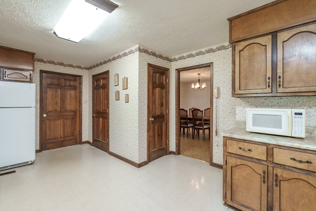 882 Gaissert Church Rd, Sparta, GA 31087 - kitchen with a chandelier, a textured ceiling, and white appliances