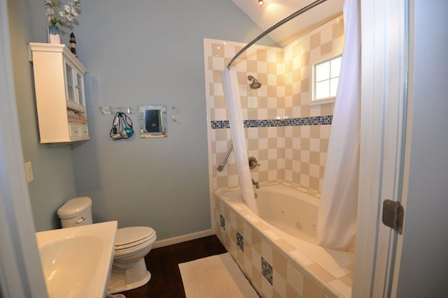 full bathroom with baseboards, toilet, tiled shower / bath combo, a sink, and wood finished floors