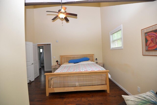 bedroom featuring baseboards, a towering ceiling, and wood finished floors