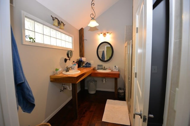 bathroom with baseboards, a sink, vaulted ceiling, and wood finished floors