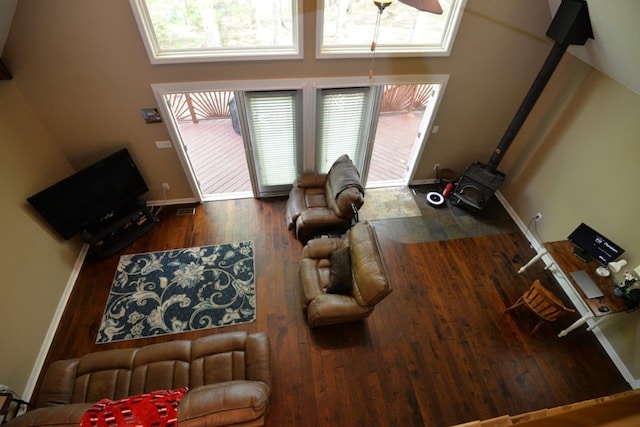 living room featuring a wood stove, plenty of natural light, baseboards, and wood finished floors