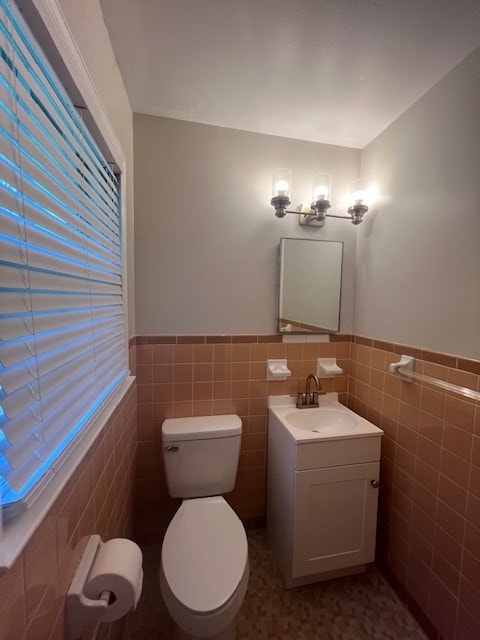 bathroom with toilet, vanity, and tile walls