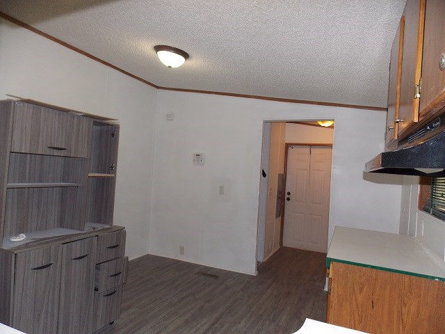 kitchen with a textured ceiling, crown molding, and dark hardwood / wood-style floors