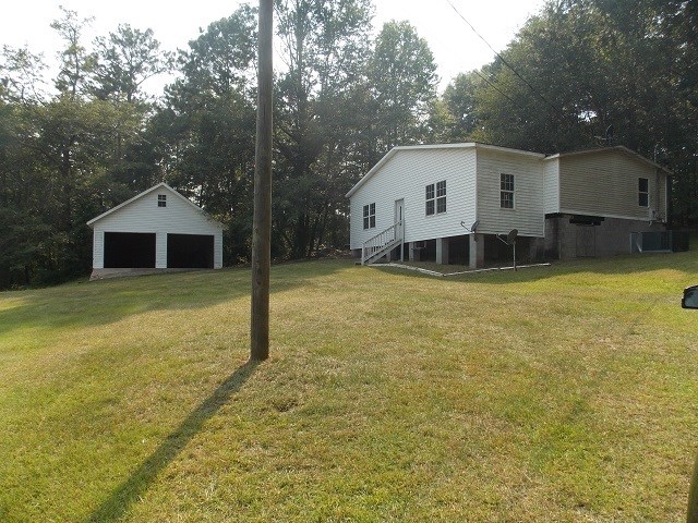 view of yard featuring an outbuilding, central AC unit, and a garage