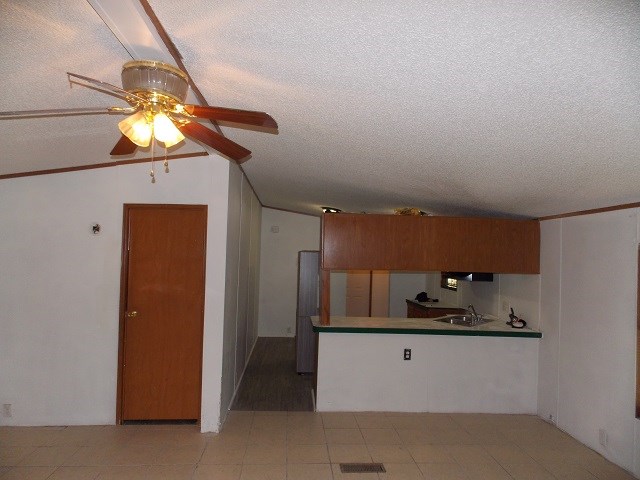 kitchen with a textured ceiling, ceiling fan, sink, and vaulted ceiling