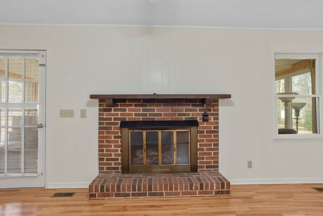 details featuring a brick fireplace, hardwood / wood-style flooring, and crown molding