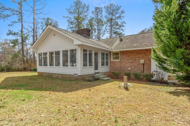 rear view of property with a yard and a sunroom