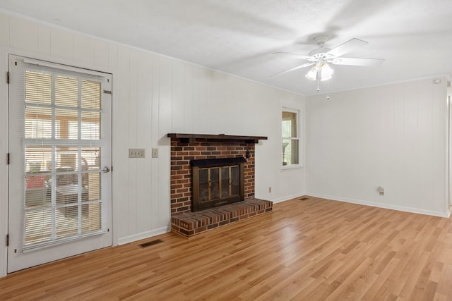 unfurnished living room with light wood-type flooring, ceiling fan, ornamental molding, and a fireplace