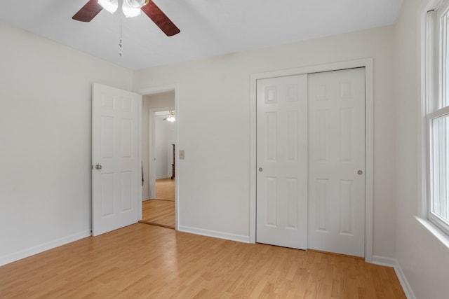 unfurnished bedroom with ceiling fan, light wood-type flooring, and a closet