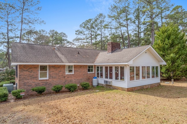 back of property with a lawn and a sunroom