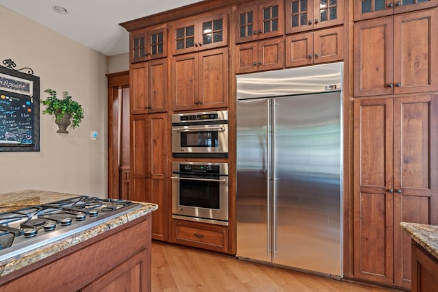 kitchen featuring light stone countertops, stainless steel appliances, and light hardwood / wood-style floors