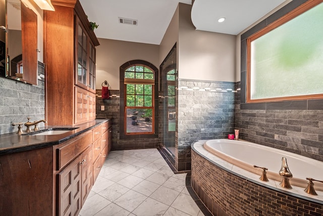 bathroom with vanity, shower with separate bathtub, and tile walls