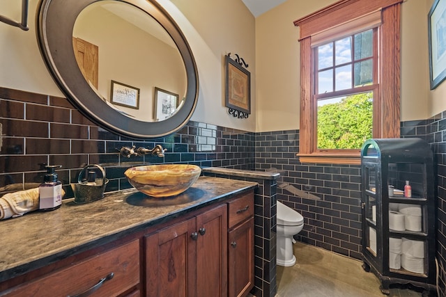 bathroom featuring tile patterned flooring, vanity, toilet, and tile walls