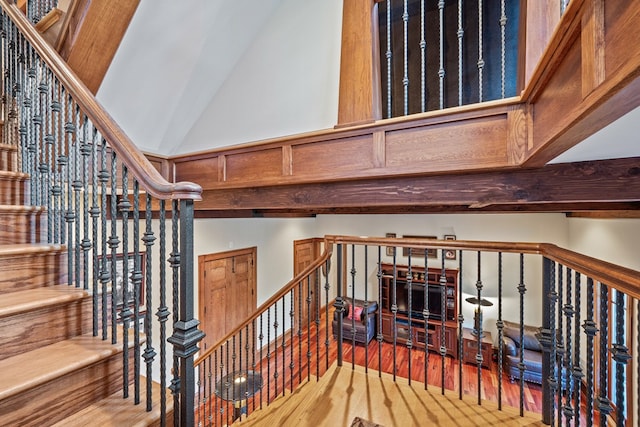 staircase with wood-type flooring and high vaulted ceiling