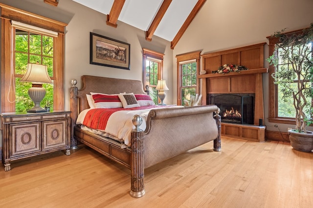 bedroom with beam ceiling, light hardwood / wood-style flooring, high vaulted ceiling, and multiple windows