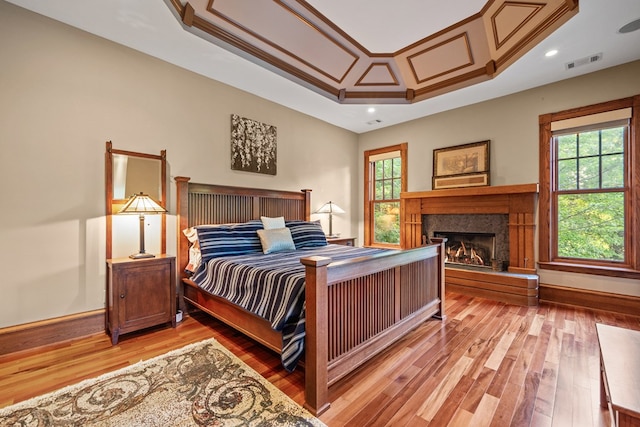 bedroom featuring a tray ceiling, light hardwood / wood-style floors, and ornamental molding