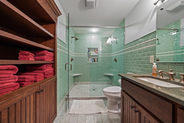 bathroom with vanity, toilet, tile walls, and walk in shower