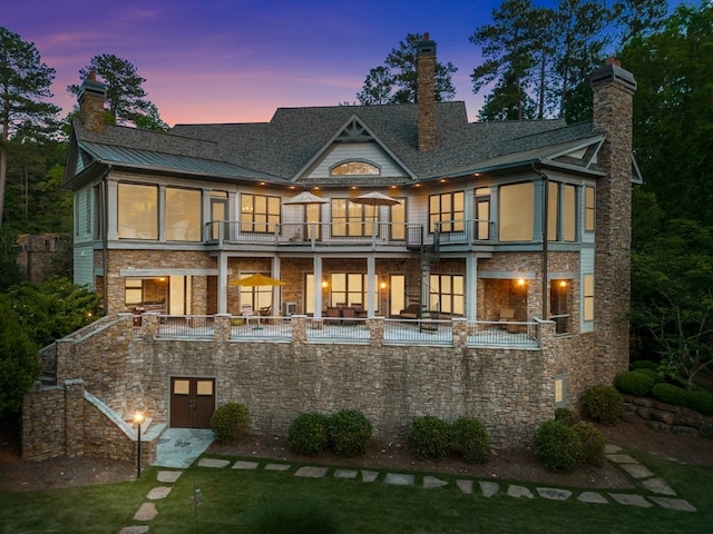 back house at dusk featuring a balcony