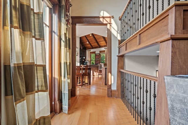 corridor featuring high vaulted ceiling, wooden ceiling, and light wood-type flooring