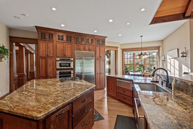 kitchen featuring an inviting chandelier, hanging light fixtures, sink, appliances with stainless steel finishes, and a large island