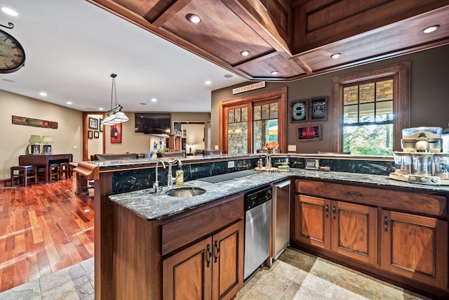 kitchen featuring kitchen peninsula, sink, decorative light fixtures, dark stone countertops, and dishwasher