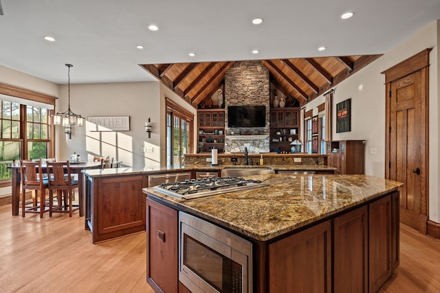 kitchen with hanging light fixtures, sink, vaulted ceiling with beams, appliances with stainless steel finishes, and wood ceiling