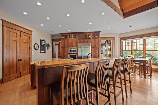 kitchen featuring a breakfast bar area, hanging light fixtures, stainless steel appliances, and light hardwood / wood-style floors