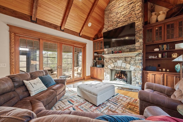 living room featuring built in features, high vaulted ceiling, beamed ceiling, a fireplace, and light wood-type flooring