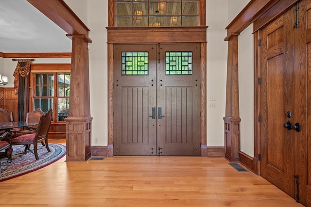 foyer entrance with ornate columns, crown molding, and light hardwood / wood-style flooring