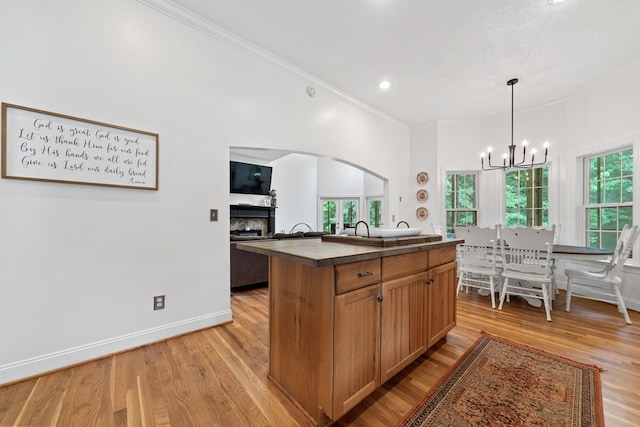 793 Greene Settlement Rd, Gray, GA 31032 - kitchen featuring a fireplace, dark countertops, arched walkways, a chandelier, and crown molding