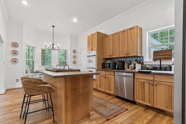 793 Greene Settlement Rd, Gray, GA 31032 - kitchen featuring stainless steel appliances, a chandelier, a breakfast bar area, light wood-style floors, and ornamental molding