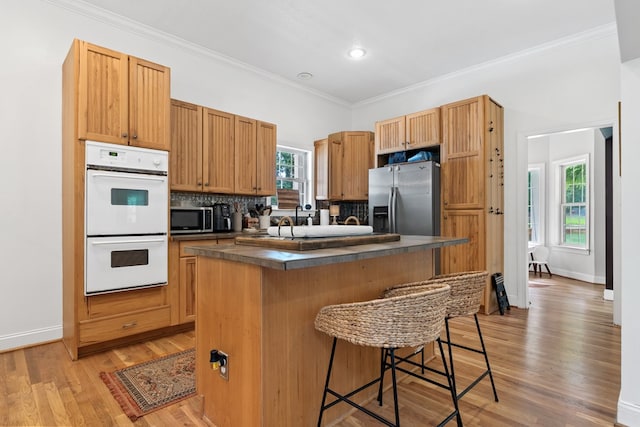 793 Greene Settlement Rd, Gray, GA 31032 - kitchen with stainless steel appliances, dark countertops, a kitchen bar, tasteful backsplash, and ornamental molding