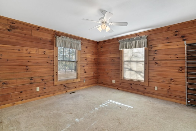 carpeted empty room with ceiling fan and wooden walls