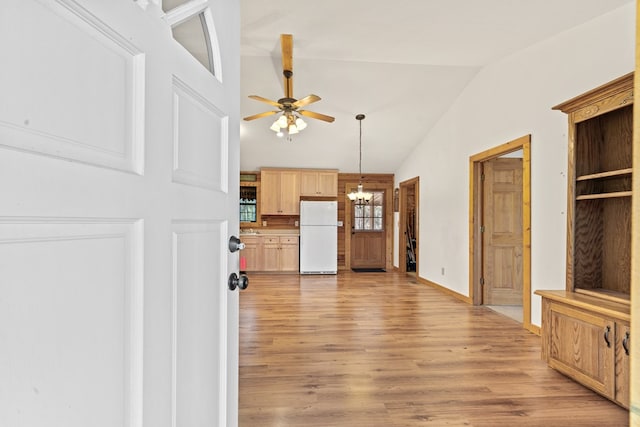 living room with lofted ceiling, ceiling fan with notable chandelier, and light hardwood / wood-style flooring