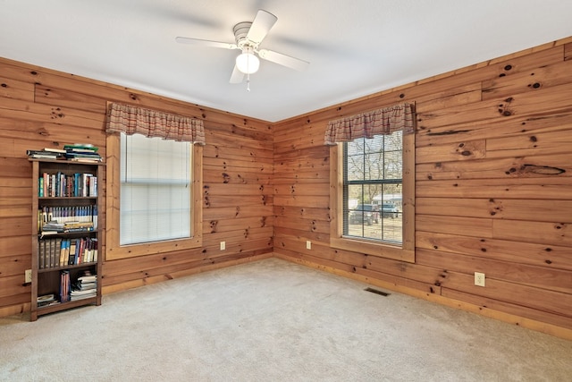 carpeted spare room with ceiling fan and wooden walls