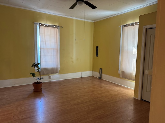 empty room featuring ceiling fan, wood-type flooring, and ornamental molding