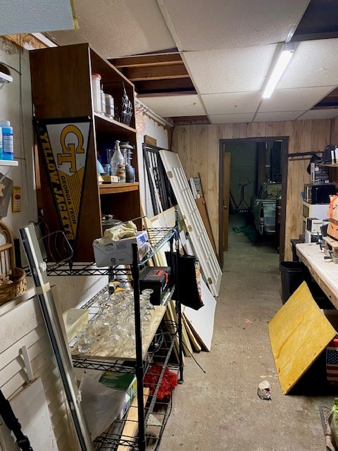 basement with a paneled ceiling and wooden walls