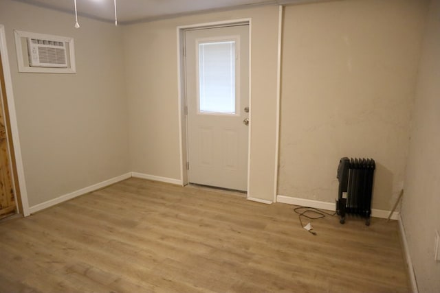doorway with radiator heating unit, light wood-type flooring, and baseboards