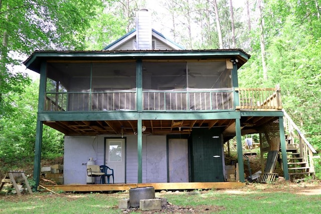 back of house featuring stairs, a sunroom, a deck, and a chimney
